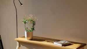 Uma mesa de madeira com um vaso branco contendo uma planta, um livro e uma luminária de mesa preta.