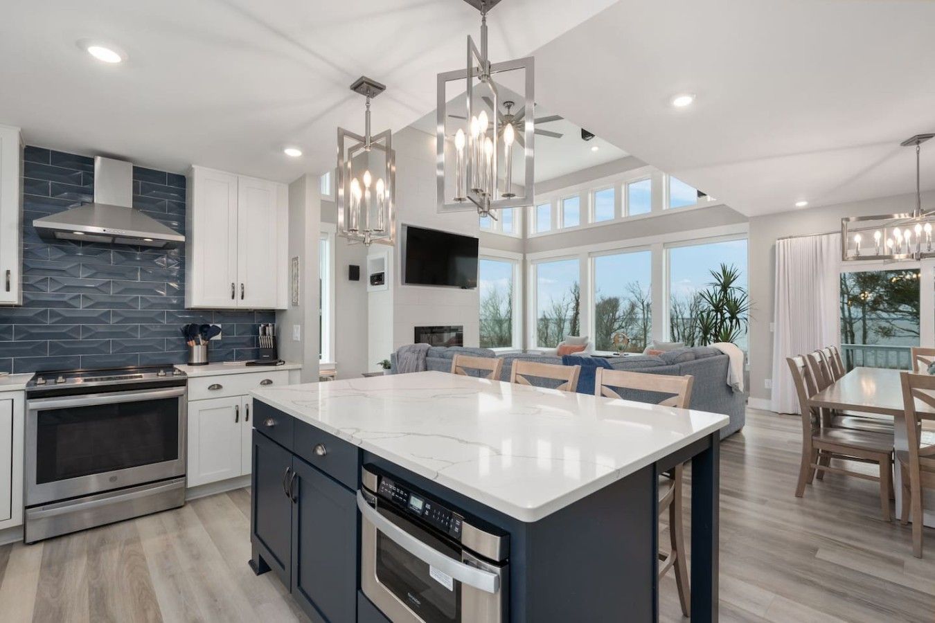 A modern kitchen with a large island, built-in appliances, and a dining area with a view.