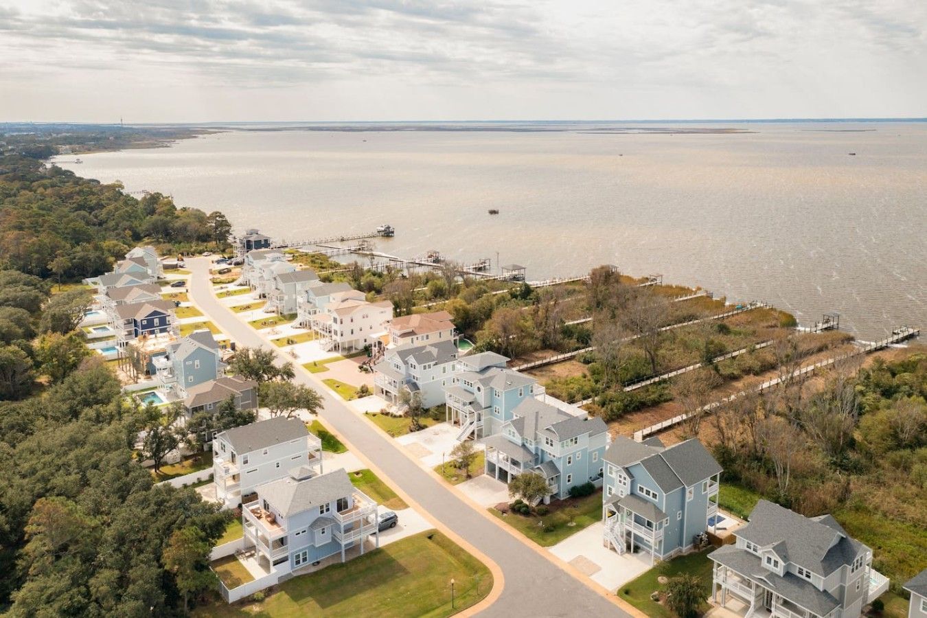 A residential area with houses along a waterfront, featuring a curved road and a dock.