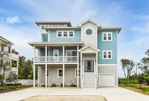 A two-story house with a balcony, a garage, and a front porch. - Baydream Believer | Soundfront, Dock, Heated Pool & Hot Tub (Corolla)