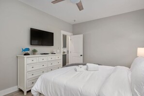 A bedroom with a bed, a dresser, a television, and a ceiling fan. - Baydream Believer | Soundfront, Dock, Heated Pool & Hot Tub (Corolla)