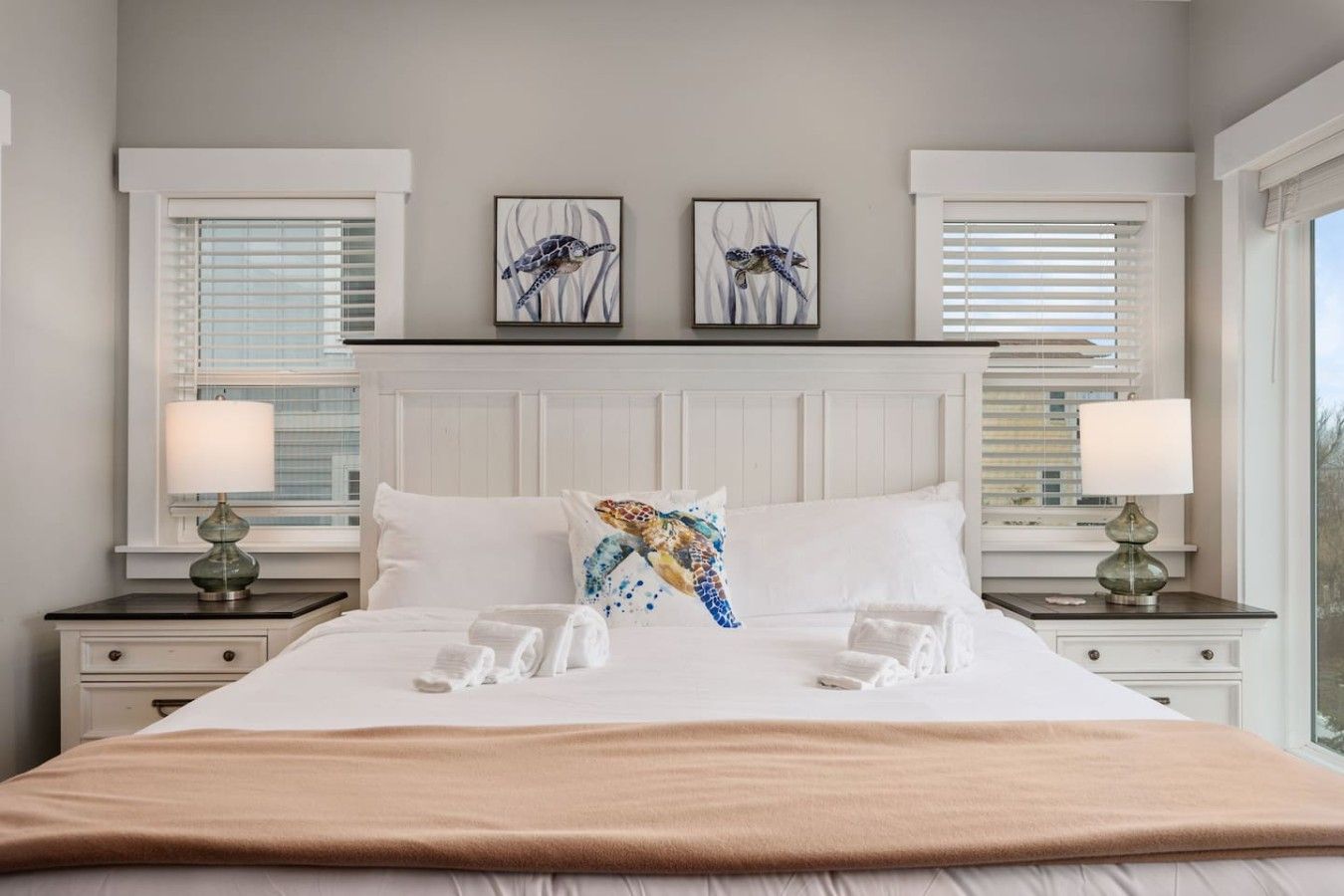 Habitación de hotel con una cama grande, dos mesitas de noche con lámparas, un cabecero y una obra de arte en la pared.
