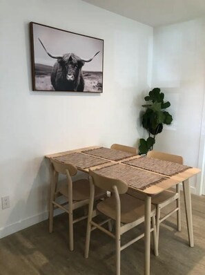 Enjoy meals in this dining area with a wooden table, four chairs, and a framed photograph on the wall.