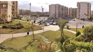 Un quartier résidentiel comprenant des immeubles d’appartements, un parking et un jardin bien entretenu.