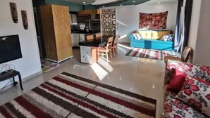 Un salon moderne comprenant un canapé, un téléviseur et un coin repas avec des chaises et une table.