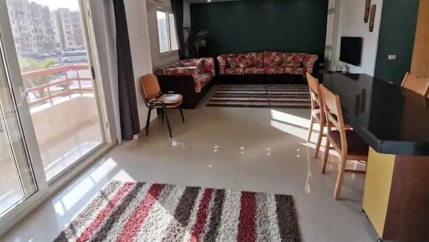 Un salon moderne avec un canapé, un coin repas et une grande fenêtre.