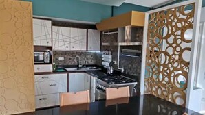 Une cuisine moderne avec un plan de travail noir, des appareils en acier inoxydable et des armoires en bois.