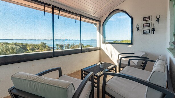 Un balcon avec vue sur la mer, une table et deux chaises.