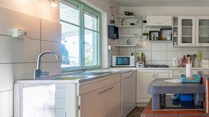 Une cuisine moderne avec des armoires blanches, un four à micro-ondes encastré et une cuisinière à gaz.