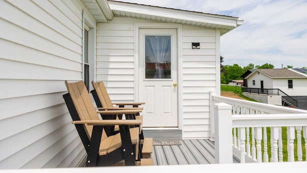 A white building with a porch, a door, and a small window. - The Wrens Nest (Baltic)
