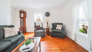 A living room with a sofa, armchair, coffee table, and a clock on the wall. - The Wrens Nest (Baltic)