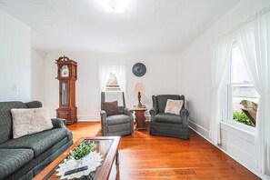 En stue med sofa, lænestol, sofabord og et ur på væggen.