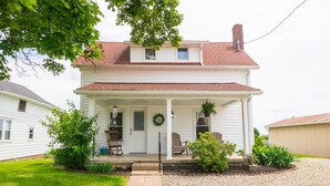 A two-story house with a porch, a front door, and a small garden area. - The Wrens Nest (Baltic)