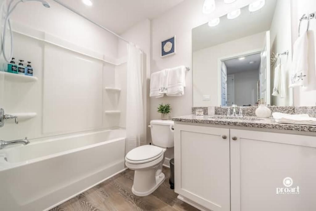A modern bathroom with a bathtub, toilet, and vanity with a mirror.