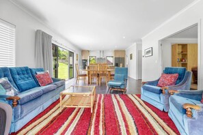 A modern living room with a sofa, armchairs, a coffee table, and a dining area with chairs and a table.