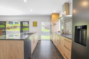 A modern kitchen with a central island, wooden cabinets, and a stainless steel refrigerator.