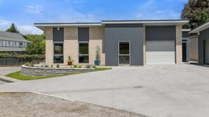 A modern two-story building with a flat roof, large windows, and a garage door. - All Good - MTB Base, Bike Wash, Sleeps 4 (Rotorua)