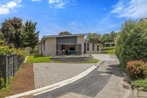 Une maison moderne dotée d’un garage, d’une allée pavée et d’une pelouse bien entretenue.