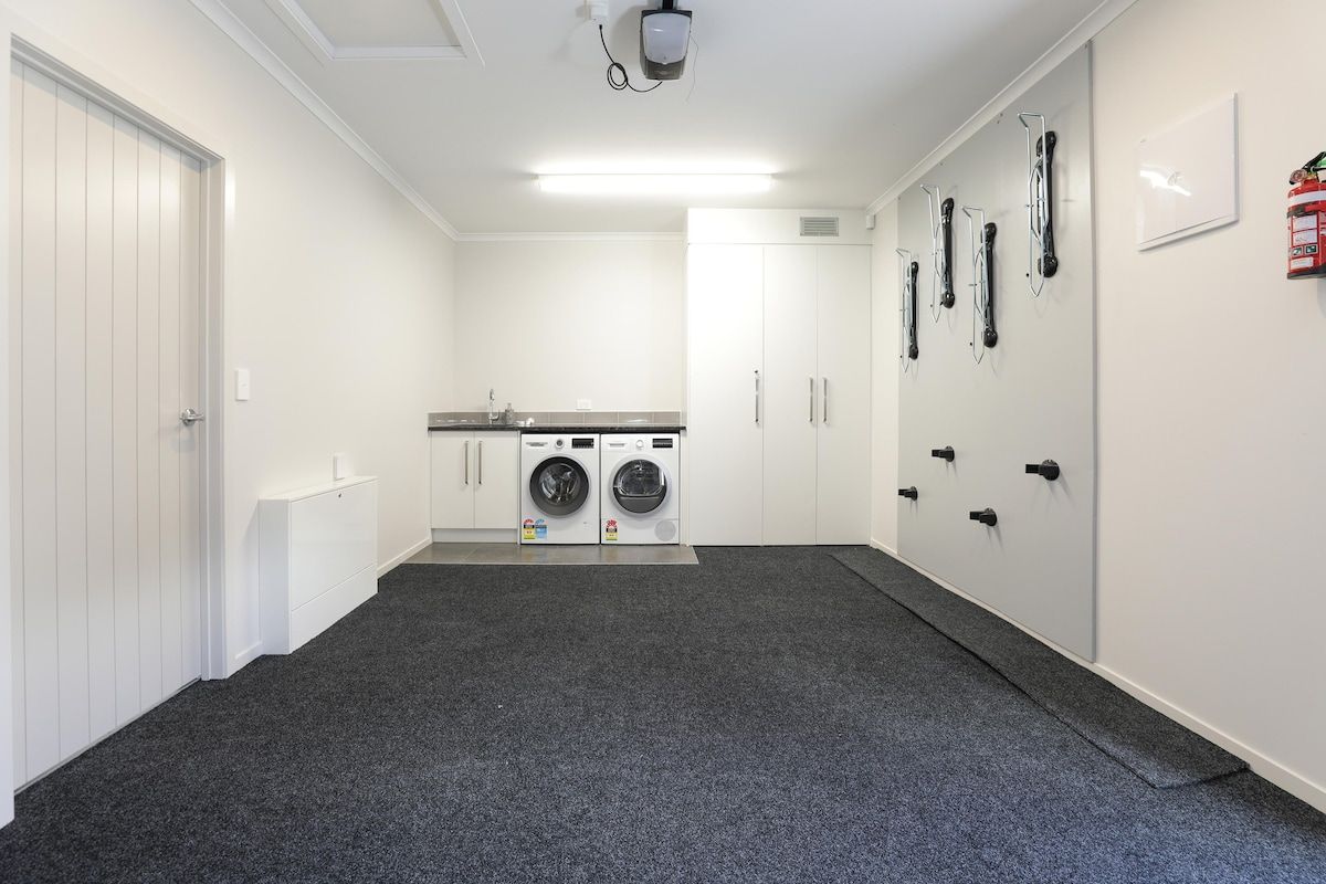 Une buanderie équipée d’un lave-linge, d’un sèche-linge et d’un extincteur fixé au mur.