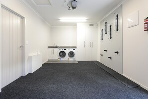 A laundry room with a washing machine, dryer, and a fire extinguisher on the wall. - All Good - MTB Base, Bike Wash, Sleeps 4 (Rotorua)