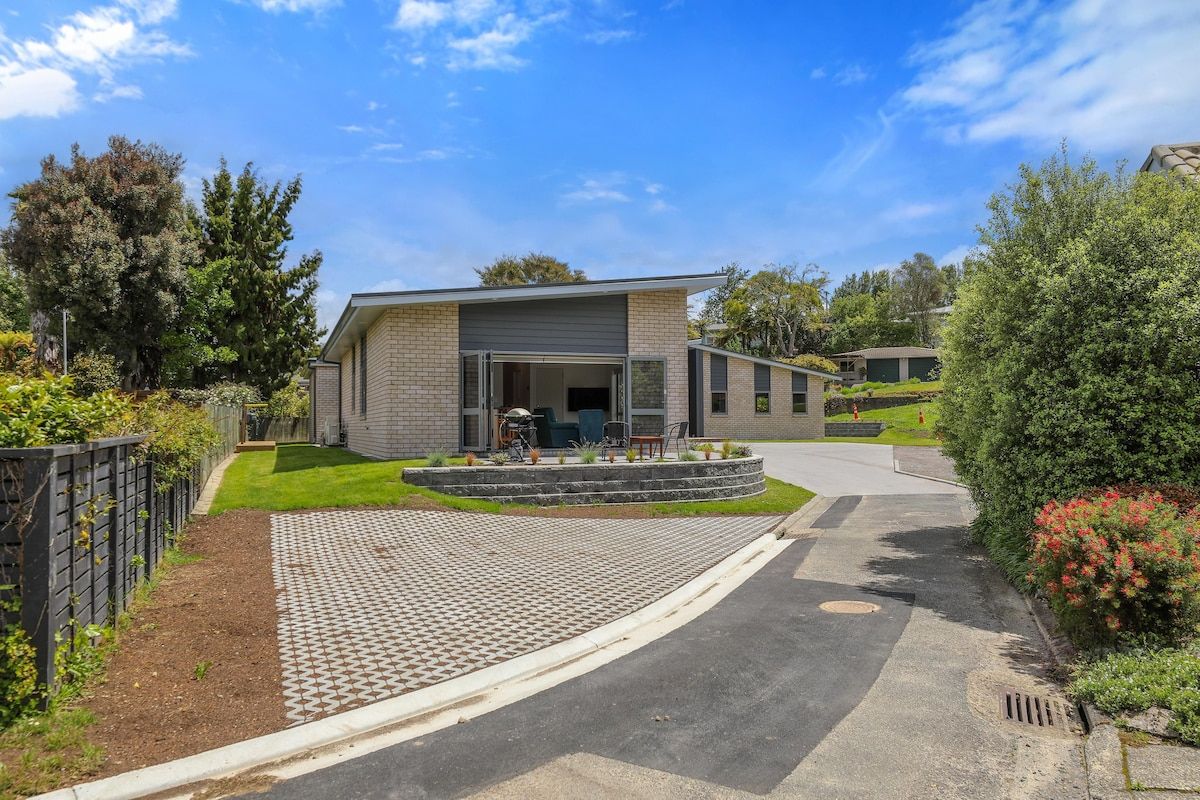 A modern two-story house with a paved driveway and a landscaped garden.
