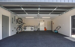 A garage with a bicycle, washing machine, and a lawnmower.