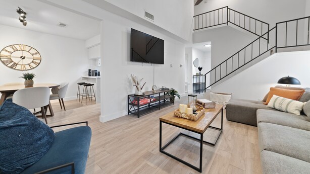 A spacious living area with a staircase, a flat-screen TV, a wooden coffee table, and a sofa. - Modern Home 7 Min from Downtown (Austin)