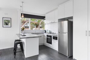 Una cucina moderna con mobili bianchi, un frigorifero in acciaio inossidabile e un forno integrato.