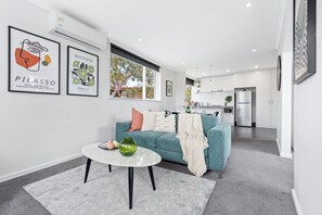 A modern living room with a sofa, a coffee table, and artwork on the wall.