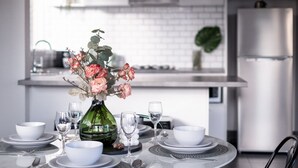 A modern kitchen with a dining table set for a meal, a green vase with flowers, and a refrigerator. - Charnwood 2BR: Homely Haven (St Kilda)