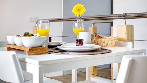 A breakfast table with white chairs, a white table, and a metal railing in the background. - Holiday Apartment 'Liomor Luxury' with Shared Pool, Wi-Fi and Air Conditioning (Caleta de Fuste)