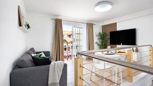 A modern living room with a sofa, a flat-screen TV, and a dining area with a table and chairs. - Holiday Apartment 'Liomor Luxury' with Shared Pool, Wi-Fi and Air Conditioning (Caleta de Fuste)