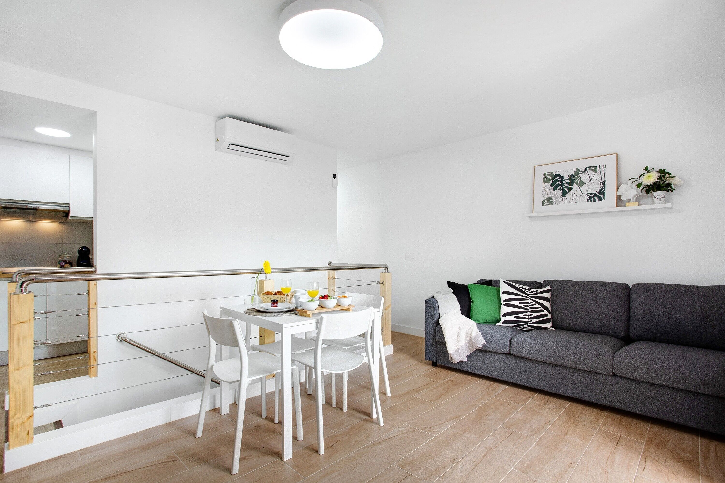 Un espace de vie moderne comprenant un coin repas, un canapé gris et un escalier.
