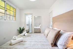 A hotel room with a bed, towels, a plant, and a view of the bathroom.