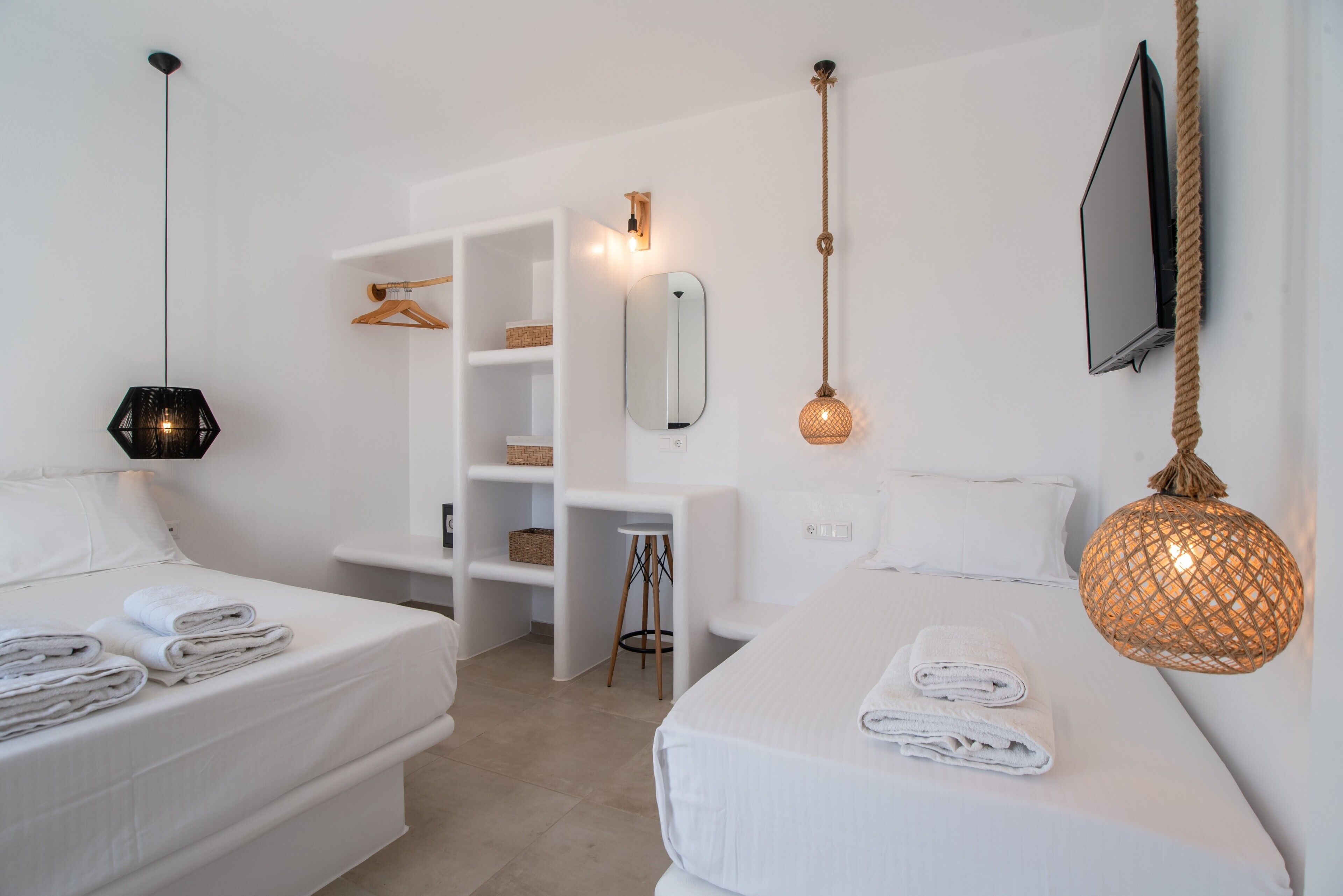 Une chambre d’hôtel avec deux lits, un bureau, un téléviseur fixé au mur et un miroir mural.
