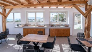 Eine moderne Küche mit Holzbalken, großen Fenstern und Blick auf die Landschaft.