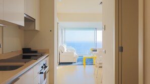A modern kitchen with a view of the sea, a dining area with a yellow table, and a white sofa. - Apartment 'Sitges Suites B' with Sea View, Wi-Fi and Air Conditioning (Sitges)