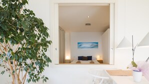 A room with a bed, a desk, a chair, a potted plant, and a painting on the wall. - Apartment 'Sitges Suites B' with Sea View, Wi-Fi and Air Conditioning (Sitges)