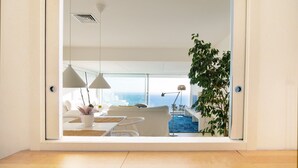 A modern living room with a large window, white furniture, and a view of the ocean. - Apartment 'Sitges Suites B' with Sea View, Wi-Fi and Air Conditioning (Sitges)