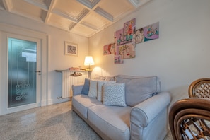A living room with a sofa, a lamp, and wall art.