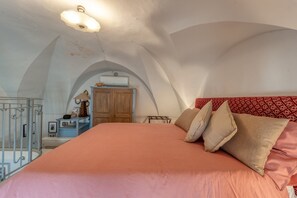 A bedroom with a large bed, a wardrobe, a desk with a chair, and a ceiling fan.