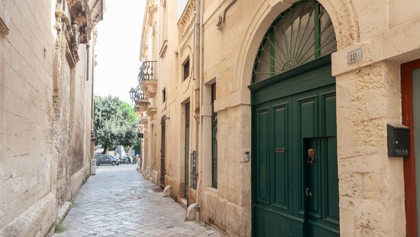 A narrow cobblestone street lined with historic buildings, a green door, and a number plaque. - Holiday Home 'La Cartapesta' with Private Terrace, Wi-Fi and Air Conditioning (lecce)