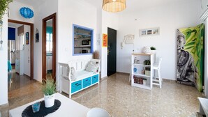 A modern interior with a kitchen, seating area, and artwork. - Apartment 'La Barca' with Shared Terrace, Wi-Fi, and Air Conditioning (Chipiona)
