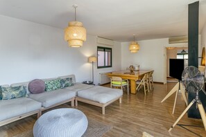 A modern living room with a sofa, ottoman, dining table, and chairs.
