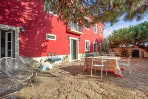A red building with a balcony, outdoor seating, and a stone floor. - Holiday Home 'São Martinho All The Best 2' with Private Terrace and Wi-Fi (São Martinho do Porto)