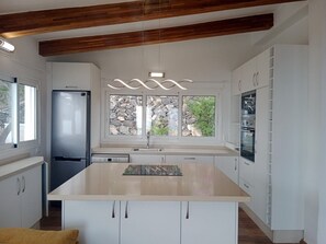 A modern kitchen with a central island, built-in appliances, and a stone wall view.