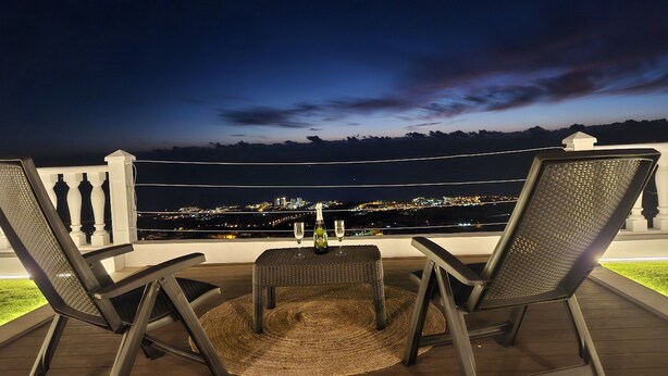Een balkon met twee stoelen, een tafeltje en een fles champagne.
