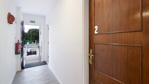 A hallway with a wooden door marked with the number 2, a fire extinguisher, and a staircase leading to an outdoor area. - Apartment 'Seashel' with Shared Terrace, Wi-Fi and Air Conditioning (Moncarapacho)