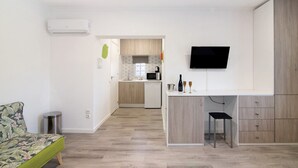 Eine moderne Wohnung mit einer Küchenzeile, einem an der Wand befestigten Fernseher und einem kleinen Essbereich.