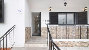 A staircase with a metal railing, a stone wall, and a window with shutters.